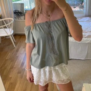 Grön off-shoulder topp med spetsdetaljer - Säljer en superfin grön off-shoulder topp i storlek S. Toppen har vackra spetsdetaljer framtill och är perfekt för sommaren. den är i L men passar s/m bättre💗💗