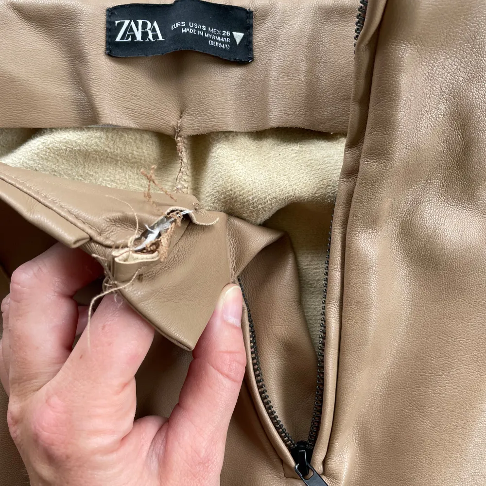 Beige ”skinnbyxor” från Zara. Högmidjade med dragkedja i sidan. Slits med dragkedja vid benslut. Byxorna är i syntetmaterial. Defekt i midjan (syns ej med plagget på, se bild).. Jeans & Byxor.