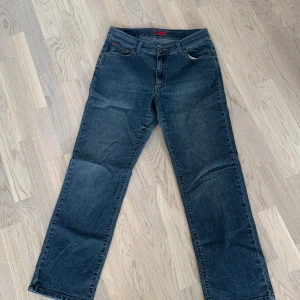 Mörkblå jeansbyxor - Säljer ett par mörkblå jeansbyxor i bra skick. De har en klassisk femficksdesign med dragkedja och knapp framtill. Byxorna har en rak passform och är medelhöga i midjan. 💛