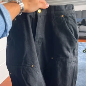 Svarta cargobyxor från Carhartt - Säljer ett par svarta cargobyxor från Carhartt. De har flera praktiska fickor och är perfekta för en avslappnad stil. Byxorna är i bra skick