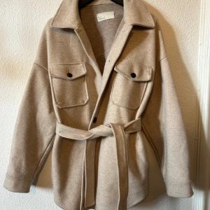 Beige overshirt från NLY Trend - Säljer en superfin beige kappa i kortmodell från NLY Trend. Sparsamt använd och i mycket fint skick. Perfekt för höst och vår!
