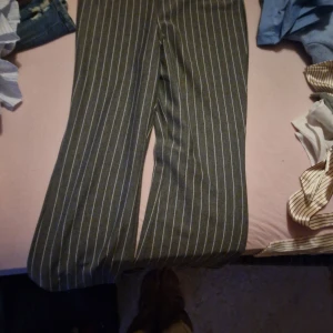 Randiga byxor från H&M Divided - Säljer ett par snygga gråa byxor med vita ränder från H&M Divided. De har en loose passform och är perfekta för både vardag och fest. Byxorna är i storlek S och är tillverkade i ett mjukt och bekvämt material.