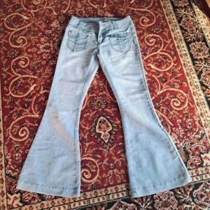 Lågmidjade ljusa bootcut jeans - Så snygga🐆 unika detaljer och svåra att få tag på💕Midjemått: 40 cm, innerbenet: 79 cm uppskattas till storlek xs