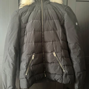 Jacka - Storlek 36, dunjacka i gott skick, från Rock and Blue Sweden. Den här delen har en avtagbar huva med dragkedja och päls. 