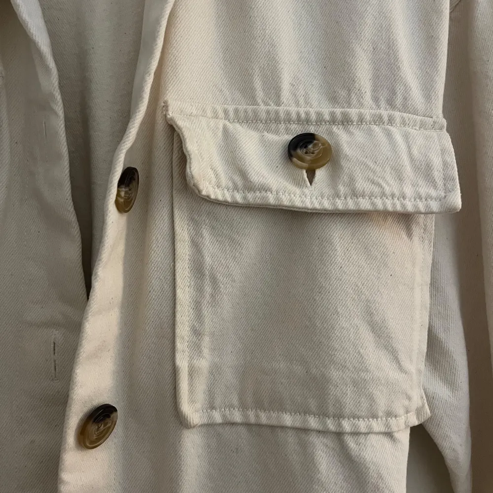 Säljer en superfin beige overshirt från Bik Bok i storlek XS. Den har långa ärmar och knappar framtill, samt två stora fickor på bröstet. Materialet känns som bomull och den har ett bälte i midjan för en snygg passform. Perfekt nu till höst!. Jackor.