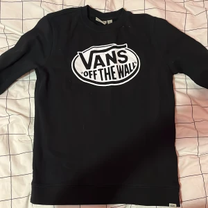 Svart sweatshirt från Vans - Säljer en svart sweatshirt från Vans i storlek L. Den har det klassiska 'Off The Wall' trycket på framsidan. Tröjan är i bomull och har långa ärmar. Perfekt för en avslappnad stil eller skate-session. Använd men i bra skick!