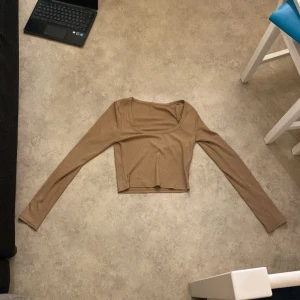 Beige ribbad topp från Shein - Säljer en snygg beige ribbad topp från Shein i storlek M. Toppen har långa ärmar och en croppad passform, perfekt för både vardag och fest. Materialet är 100% polyester vilket gör den mjuk och bekväm att bära. Passar bra till jeans eller kjol för en stilren look.