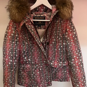 Woolrich dunjacka - Superfin dunjacka/puffer från woolrich, perfekt till ett par svarta skidbyxor i backen eller till vardags. Jättefint skick utvändigt, enda deffekten är en lagad reva i fodret på insidan men det syns inte vid användning. Passar en S/M, storleken är L men jackorna är lite små i storlekarna. Kan gå ned i pris vid en snabb affär. Äkta pälskrage.