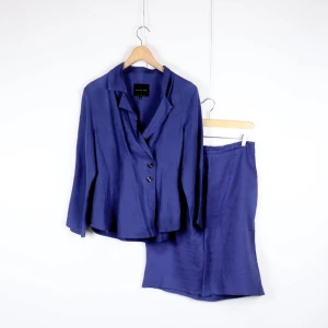 Bitte Kaj Rand - Blå kavaj och kjol i linne - Snygg blå kavaj och matchande kjol från Bitte Kaj rand. Kavajen har en klassisk krage och knäpps med två knappar framtill. Kjolen är i samma blå nyans och har en elegant passform. Perfekt för både kontoret och festliga tillfällen. 🌀