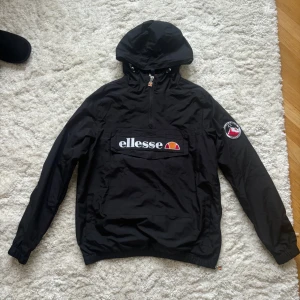 Jacka - Säljer en svart vindjacka från Ellesse i mycket bra skick. Jackan har en stor logga på bröstet och en praktisk ficka framtill. Den har en huva och dragkedja vid halsen. Perfekt för höst och skidåkning