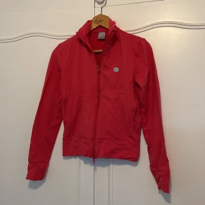 Rosa sport jacka från Nike - Säljer en snygg rosa jacka från Nike i bra skick. Jackan har en dragkedja framtill och är långärmad. Perfekt för vår och höst, med en normal passform som funkar till både träning och vardag. Den är gjord i ett lätt och bekvämt material.