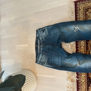 Blå jeans från Replay - Säljer ett par snygga blå jeans från Replay i modellen Anbass. De har en cool distressed look med slitningar på knäna och en bekväm passform. Perfekta för en casual stil och funkar året runt. 🕶️ bra skick, storlek 33:32 pris kan diskuteras
