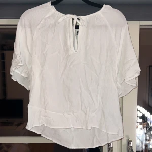 Vit blus med knytband - Säljer en söt vit blus från Vero Moda i storlek S. Den har korta ärmar och ett knytband vid halsen för en extra detalj. Perfekt för vår och sommar, och passar både till vardags och fest. Materialet är lätt och luftigt, vilket gör den bekväm att bära hela dagen.