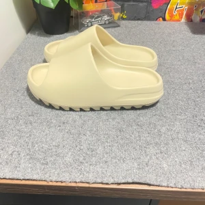 Yeezy slides  - Säljer nu ett par riktigt feta slides för dig som har storlek 40-41 skorna saknar låda och därav priset.ÄR ENDAST ANVÄNDA INOMHUS. Dem är nästan helt nya och är i mycket bra skick Det går säkert att pruta lite så kom med rimliga förslag|| frågor eller funderingar? Ingen fara hör av dig bara så svarar vi så snabbt som möjligt 😁
