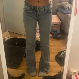 Blå bootcut jeans med broderade fickor - Säljer ett par snygga blå bootcut jeans i bra skick. De har en låg midja och coola broderade detaljer på bakfickorna💝