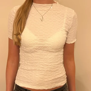 Vit ribbad topp - Säljer en snygg vit ribbad topp i mycket bra skick. Den har en tight passform och korta ärmar, perfekt för sommardagar eller en avslappnad fest. Materialet är mjukt och stretchigt, vilket gör den superbekväm att bära. Passar perfekt till jeans eller kjol!