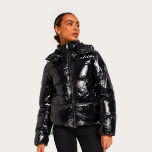 Svart glansig pufferjacka - Säljer en snygg svart glansig pufferjacka med dragkedja från Nelly . Använd några gånger inga skador på jackan. Säljer pågrund av jag köpt en ny jacka. Perfekt för kalla dagar med sin varma och vadderade design. Jackan har en hög krage och långa ärmar, vilket gör den idealisk för vinter pch höst.