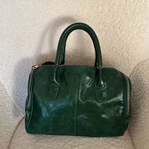 Grön vintage läderhandväska - Grön vintageväska i äkta läder från DON DONNA. Den är i ganska bra skick och den har använts väldigr få gånger. Den har ett par repor på handtaget, men annars i bra skick.