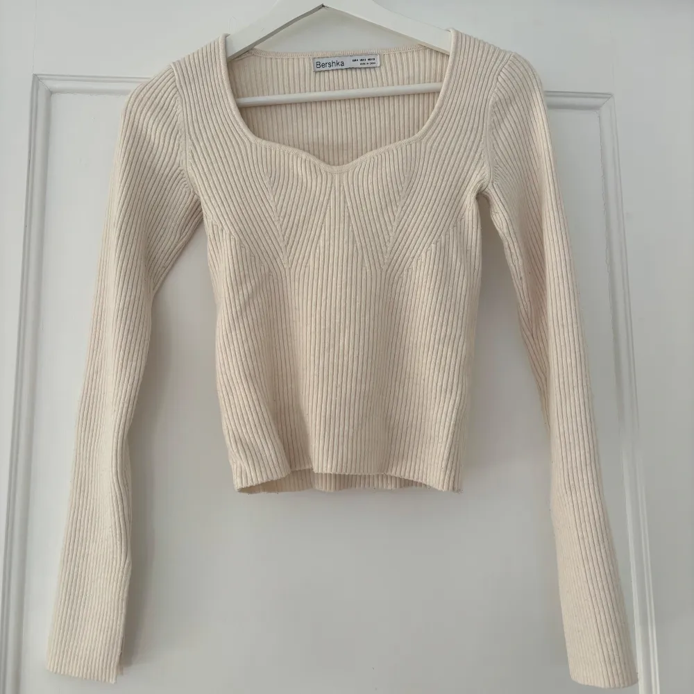 Säljer en snygg beige/vit ribbad tröja från Bershka. Den har långa ärmar, perfekt för höst och vår. Tröjan är i bra skick men har en liten fläck på ärmen. Passar perfekt till både jeans och kjol!. Tröjor & Koftor.