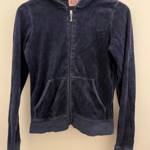 Mörkblå kofta från Juicy Couture - Säljer en mörkblå kofta från Juicy Couture i mjukt material. Den har dragkedja framtill och en mysig huva. Perfekt för en avslappnad stil. Några små slitningar vid ärmsluten, men annars i bra skick. Perfekt för höst och vår!😊💘💙Storlek M men väldigt liten i storlek så skulle säga att den passar S/Xs🤪