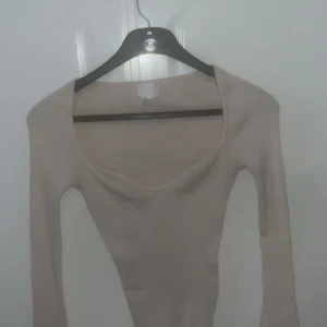 Beige ribbad tröja - Säljer en superfin beige ribbad tröja med lång ärm. Perfekt för både vardag och fest! Den har en snygg, lite djupare halsringning som ger en elegant touch. Tröjan är i bra skick och passar perfekt till höst- och våroutfits. Skön och stretchig i materialet.