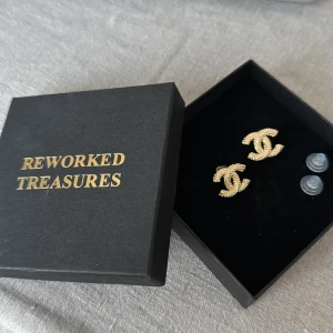 Guldiga örhängen från Reworked Treasures - Säljer ett par snygga guldiga örhängen från Reworked Treasures. De har en glittrig finish och kommer i en elegant svart ask. Perfekta för att ge en touch av glamour till vilken outfit som helst. Passar både till vardag och fest!