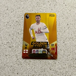 Fantastiskt fotbollskort - En Panini Adrenalyn Plus 2024 fotbollskort med "Golden Baller"-design. Kortet har en gyllene bakgrund med en spelare i vit tröja. Detaljer som DEF, CTRL och ATT är alla 100, vilket ger en total på 300. Kortet har Premier League-loggan och är märkt med "MADDISON". Baksidan har en gyllene Premier League-logga. Uppskattar ej skambud men priset är ej hugget i sten