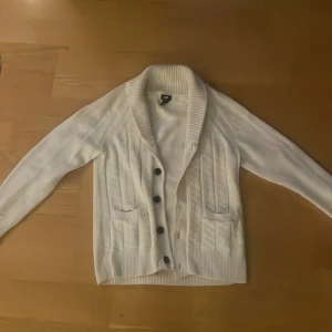 Stickad cardigan - Säljer en stilren vit kofta från H&M i storlek S. Den är stickad med snygga knappar och har två praktiska fickor framtill. Perfekt för både höst och vinter, och funkar lika bra till vardags som till lite finare tillfällen. Koftan är i mycket bra skick. Modellen är 177 och väger 57kg! Frågor eller funderingar så hör av dig 🤙 Mvh JacobsCloset 