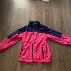 Rosa och marinblå vindjacka från McKinley - Säljer en snygg och praktisk vindjacka från McKinley i rosa och marinblått. Jackan har en dragkedja framtill och elastiska muddar vid ärmsluten. Perfekt för vår och höst när det blåser lite extra. Den är i bra skick och redo för nya äventyr!