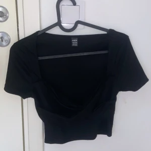 Svart kortärmad topp från Shein - Snygg svart topp från Shein i storlek M. Den har en djup v-ringning och korta ärmar, perfekt för en utekväll eller fest. Materialet är mjukt och stretchigt för en bekväm passform. Passar bra till både jeans och kjol!