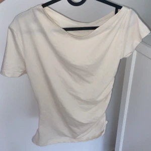 Vit offshoulder topp - Säljer en stilren vit offshoulder topp i mjukt material. Perfekt för sommardagar eller en avslappnad kväll. Toppen har en enkel design med korta ärmar och en bekväm passform. Passar bra till både jeans och kjol!