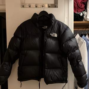 Säljer en svart pufferjacka från The North Face, inhandlad vintern 2022. Den har ett litet hål på armen som jag lagat (se bild 4), men det syns knappt. Väldigt varm och perfekt nu för vintern.