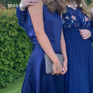 Mörkblå långklänning med slits - Elegant mörkblå långklänning i satin med en stilren slits på sidan. Klänningen har en vacker öppen rygg och smala axelband som ger en sofistikerad look. Perfekt för speciella tillfällen där du vill glänsa. Köpt från bubbelroom sicka för fler bilder första och andra är egna 