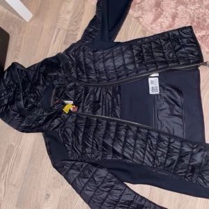 Svart pufferjacka från Peak Performance - Säljer en svart pufferjacka från Peak Performance med huva och dragkedja. Jackan har en quiltad design och är perfekt för kyligare dagar. Den är lätt och smidig att bära, vilket gör den idealisk för både stad och natur. Den är även oanvänd ny och fräsch. Fler frågor och bilder på skannings märket kan tas privat. Pris kan även diskuteras!