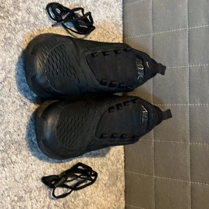 Svarta sneakers från Nike - Snygga svarta sneakers från Nike med en modern design. Skorna har en diskret Nike-logga och är utrustade med snörning för en säker passform. Perfekta för en stilren look.