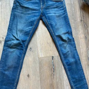 Blå jeans från Tiger of sweden - Snygga blå jeans med en klassisk femficksdesign och knappgylf. De har en straight passform och är perfekta för en avslappnad stil. Märkeslappen sitter på baksidan av midjan. Storlek 31/32
