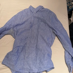 Blå linneskjorta från C  - Säljer en stilren blå linneskjorta från märket C. Skjortan har en klassisk krage och långa ärmar, perfekt för en avslappnad men ändå snygg look. Den är i regular fit och passar bra till både jeans och chinos.