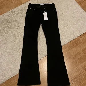Svarta bootcut jeans - Snygga svarta bootcut jeans med låg midja. Perfekta för en stilren look. De har en klassisk design med dragkedja och knappar framtill. Aldrig använda säljer pga av att dom är för stora💗