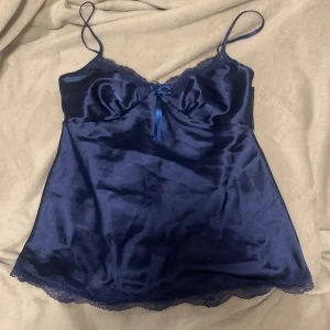 Mörkblå satinlinne med spetsdetaljer - Elegant mörkblå satinlinne med tunna axelband och spetsditaljer. Helt ny, aldrig använt då den inte passade i övre delen.