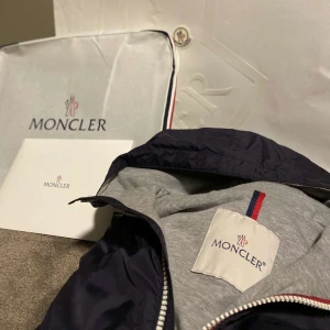 Marinblå Moncler Windbreaker - Säljer nu denna fräscha Marinblåa Windbreaker från moncler| den är i storlek xs och passar dig som är 13-15| nypris runt 6-8 tusen kr| Perfekt nu inför våren/sommaren |100% äkta och inga defekter| vid frågor eller funderingar är det bara att höra av sig!