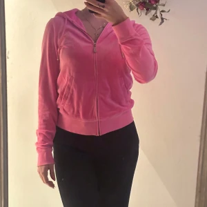 Juicy couture kofta  - Säljer en snygg Juicy Couture rosa kofta med dragkedja framtill. Koftan har en huva och långa ärmar, perfekt för en avslappnad stil. Den är mjuk och bekväm, idealisk för vardagsbruk. Färgen är exakt som på bild nr.3 