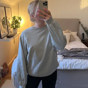 Grå sweatshirt med rihnstone - Säljer en stilren grå tröja med små paljettdetaljer som ger en subtil glans. Tröjan har en normal passform och långa ärmar, perfekt för en avslappnad look. Passar bra till både jeans och kjol. Perfekt för höst och vår!