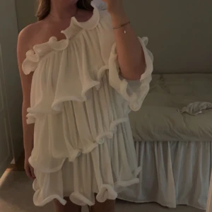 Vit offshoulder klänning - Säljer en superfin vit offshoulder klänning med volanger. Perfekt för sommarens alla tillfällen. Klänningen har en luftig passform och är tillverkad i ett lätt material som ger en skön känsla. Ett måste i garderoben för den som älskar stilrena plagg med det lilla extra. Hade den på min studnet! Sååå fin! Köpt rätt dyr men kan gå ner i pris vid snabbt köp!