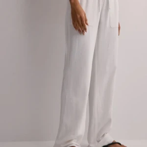 Vita linnebyxor - Snygga vita linnebyxor med en avslappnad passform. Perfekta för varma dagar med sin lätta och luftiga känsla. De har dubbla lager tyg vilket gör att dom inte är genomskinliga. De är knappt använda men har krympt i tvätten så att längden är kortare än vanligt. De går över fötterna på mig som är 180