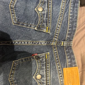 Blå bootcut jeans från Levis original pris 1.300 men säljs för 700 - Snygga blå bootcut jeans med klassisk gul söm och femficksdesign. Perfekta för en avslappnad stil. Märkta med 'Noughties Bootcut' och storlek 27 från Levis. Aldrig andvända eftersom dom va för korta. 