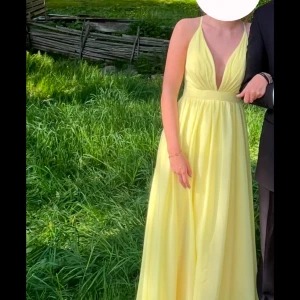 Gul långklänning med v-ringning - Säljer min gula balklänning. Har bara sytt axelbanden lite kortare men finns kvar om man skulle vilja ta bort det. Den var en liten slits vid benet på ena sidan men knappt något som syns Storlek: US34-UK8-EUR34  Passar mig som brukar ha 36
