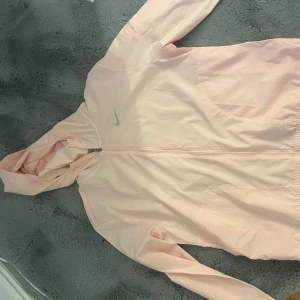 Nike running, utomhus tunn”  jacka” - Tunn lätt utomhus sportig Nike  jacka, tunt material och sportigt material, aldrig använt, köpte för ca 2 år sedan och den har bara hängt i garderoben eftersom jag inte är ute och går utan mest på gymmet. Den är alltså i nyskick och perfekt för dig som gillar att gå ut på promenader.strlk S, funkar nog som M också