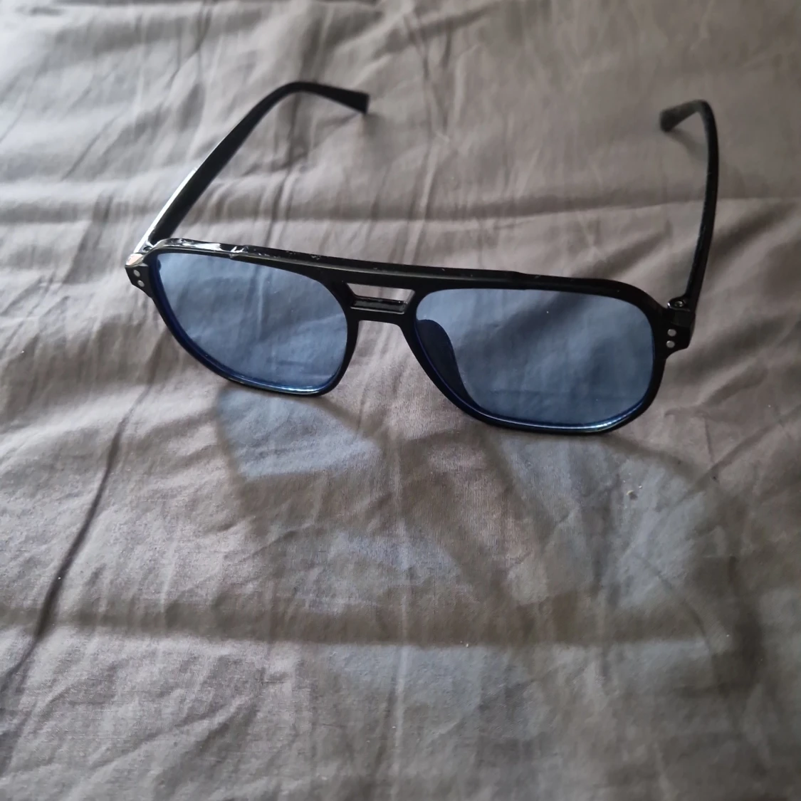 Solglasögonen ljusblått glas och svarta bågar 