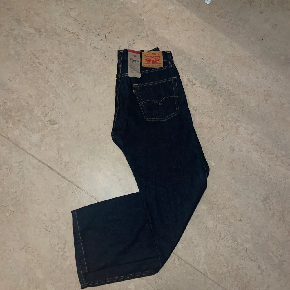 Säljer ett par Levi's 555 '96 Relaxed Straight jeans i mörkblå denim. De är tillverkade av 100% bomull och har en avslappnad passform med raka ben. Perfekta för en casual look och passar till alla tillfällen. Helt nya och oanvända. Jeans & Byxor.