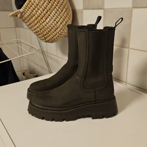 Svarta boots med grov sula - Mörkbruna boots/ Chelseaboots med en rejäl sula och resår. Sköna att gå i och känns inte för chunky. Ser lite fläckiga ut på bilden men det är för att de blivit av torkade.  Använda fåtal ggr.